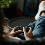Close-up of woman gaming with a controller, feet propped up, enjoying leisure time indoors.