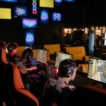 Group of gamers participating in an online tournament at a modern internet cafe.