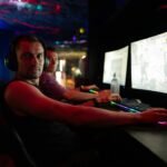 Men playing video games in a dimly lit room.