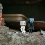 Two skeleton figures stand on rubble